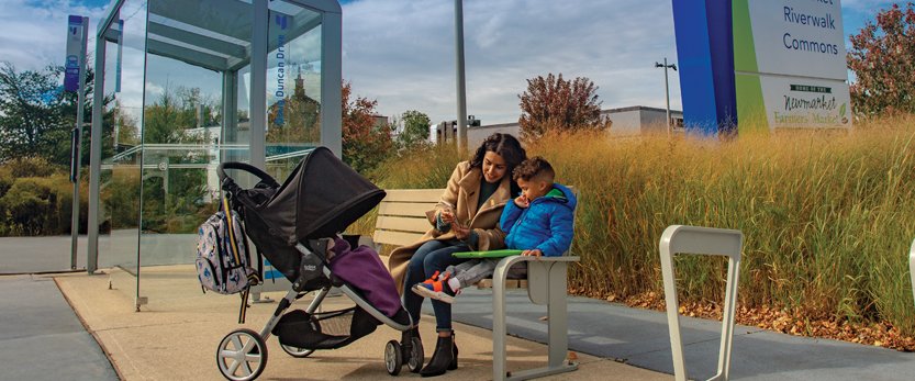 young family sitting on a bench at a bus stop