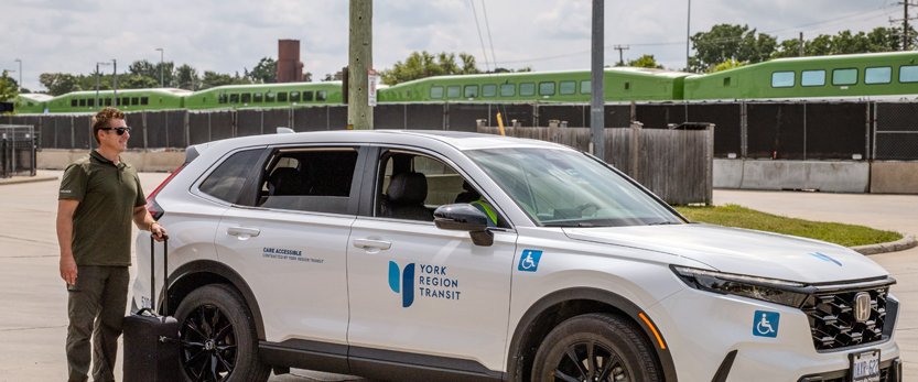 a transit rider beside a YRT On-Request vehicle in the Aurora GO Station parking lot