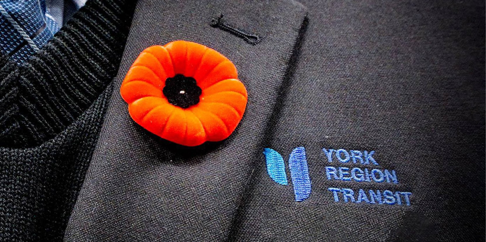 poppy pin on a bus driver uniform showing the YRT logo